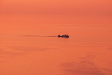 Fishing boat on a warm sunset, minimalistic photo. Golden Horizon Voyage
