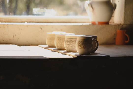 Ceramic mugs in sunlight on rustic table by window