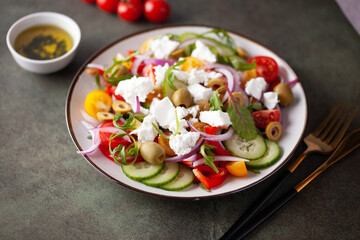 Greek salad of fresh cucumber, tomato, sweet pepper, arugula, red onion, feta cheese and olives with olive oil. Healthy food.