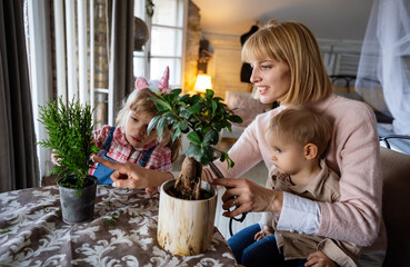 Happy single parent, woman with a little son is planting houseplants at home. Home gardening