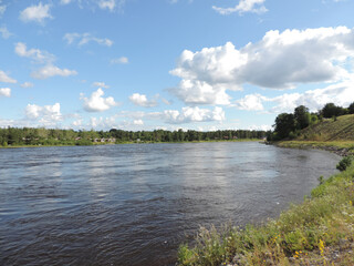 Ferienhäuser säumen das Ufer eines Flusses in Schweden, Stromschnellen bei Flut und Ebbe