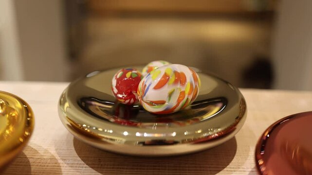 A close-up of colorful Easter eggs displayed on a shiny plate, featuring intricate designs and bold hues. The vibrant colors and artistic patterns bring a festive and cheerful atmosphere to any celebr