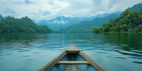 Boat on a serene mountain lake surrounded by misty hills under cloudy sky.