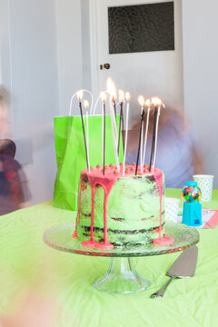 birthday cake with candles and blurred kids in the background