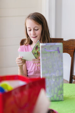 12 year old girl reading the card before opening presents at her party