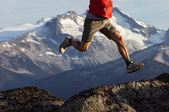 Trail runner soaring over rugged terrain with glaciers in view.