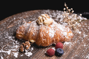 Сake croissant with chocolate with powder and almonds nuts and raisins.