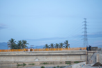 Construction site of a bridge with palm trees and electricity pylons