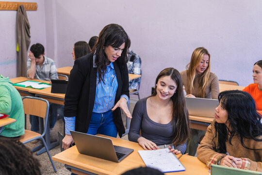 High school teacher helping students studying with laptop and notebook