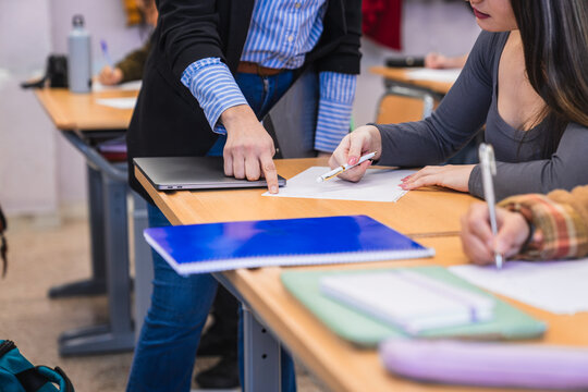 Teacher helping student during exam in high school classroom