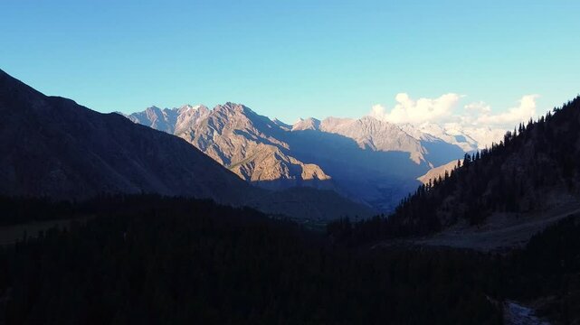 Aerial view of the majestic mountains surrounding Rama Valley in Chitral, Pakistan, bathed in the golden light of the setting sun