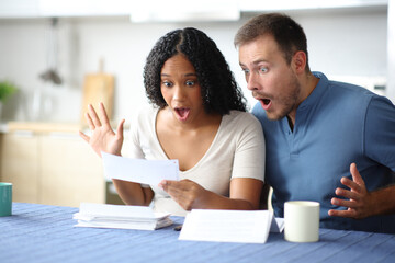 Amazed couple reading bank statement in the kitchen