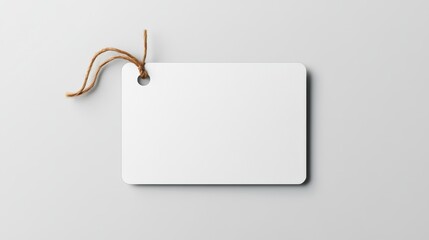 Blank white tag with a string on a gray background, perfect for branding or minimal design.