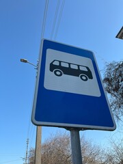  A classic blue and white bus stop sign prominently displayed against a clear blue sky. Shot from a low angle. Ideal for illustrating public transportation, commuting, urban life, and travel concepts