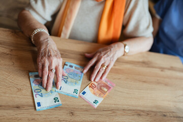 Obraz premium Close up of old woman laying banknotes on table.