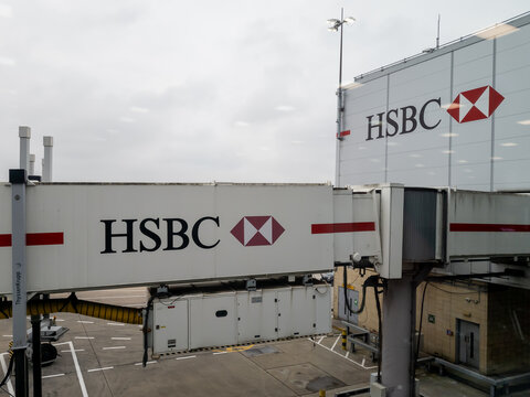 Heathrow airport. UK-02.12.2025. A jet bridge with the name sign and logo of HSBC bank.