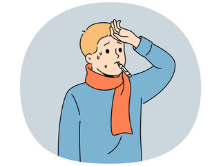 Sick flu boy with thermometer in mouth touching forehead with fever and in need antibiotics to fight infection. Sick child suffers from disease caused by hypothermia and problems with immune system