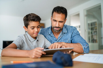 Father and son using tablet and doing homework
