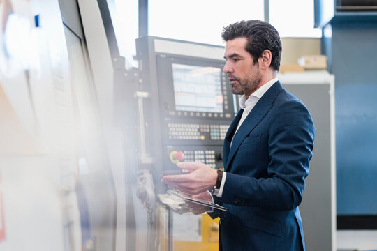 Businessman using tablet at a machine in a factory