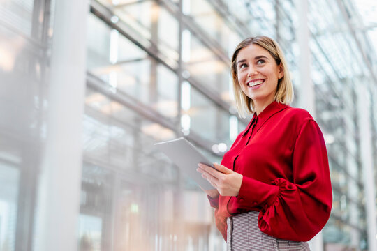 Businesswoman in red blouse holding a tablet in a modern office
