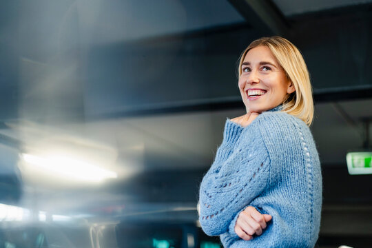 Portrait of a smiling woman in a blue sweater indoors with a dark background