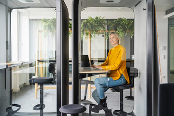 Woman in a modern office booth working on a laptop in Germany