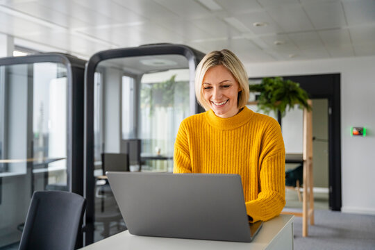 Smiling woman working on a laptop in a modern office