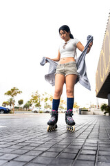 Young woman putting on sweater while inline skating in urban setting