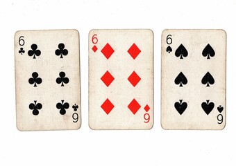 A hand of vintage playing cards showing three of the same value on a white bckground.