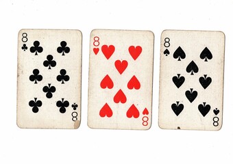 A hand of vintage playing cards showing three of the same value on a white bckground.
