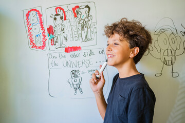 Portrait of happy boy drawing on a whiteboard