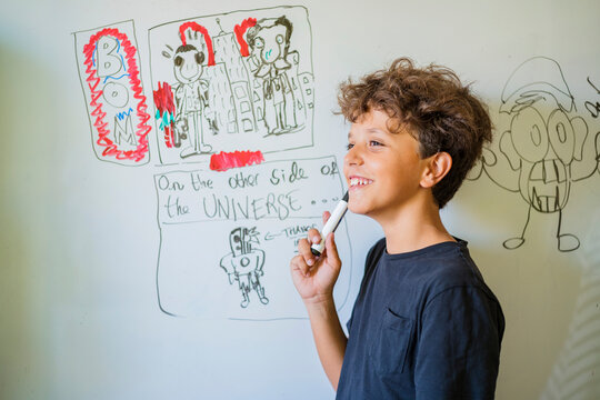 Portrait of happy boy drawing on a whiteboard