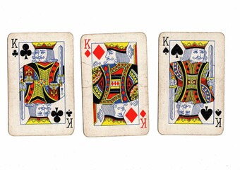A hand of vintage playing cards showing three of the same value on a white bckground.