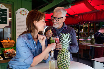 Mature couple drinking a healthy juice at a market stall