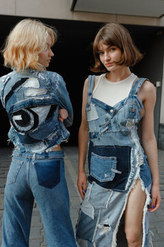 Two young women in denim fashion on the street, one looking at the camera