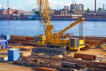 A construction crawler crane on the shore installs supports in the daytime during the construction...