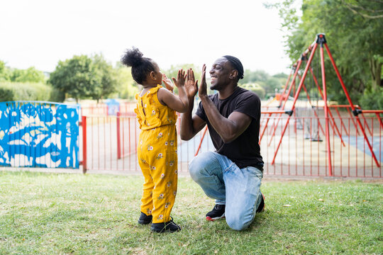 Happy father and daughter playing a clapping game in a park