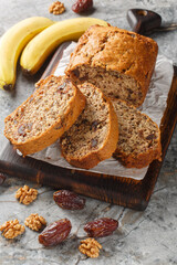 Homemade Date banana walnuts bread loaf close-up on wooden board on table. Vertical