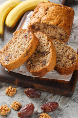 Date banana nuts diet bread close-up on wooden board on table. Vertical