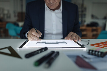 Close-up of senior businessman drawing on shining tablet