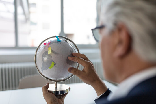 Senior businessman looking at globe with post its