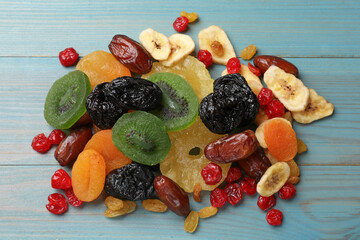 Mix of different dried fruits on light blue wooden table, top view
