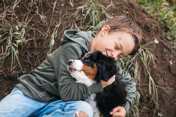 Boy playing with his Bernese mountain dog in the garden