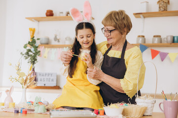 Happy easter! A grandmother and her granddaughter painting colorful eggs
