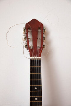 Close-up of broken guitar by white wall