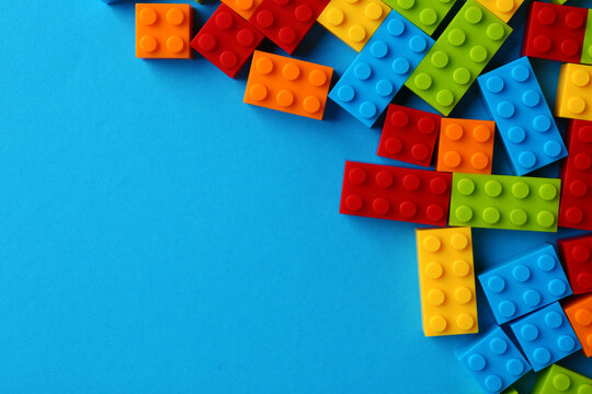 Constructor toy. Many colorful building blocks on light blue background, flat lay. Space for text