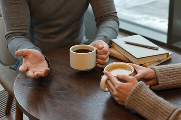 Colleagues talking during coffee break at wooden table in cafe, closeup