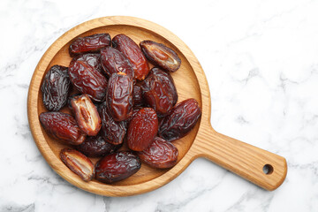 Many tasty dried dates on white marble table, top view