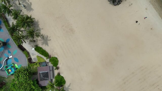 Flight with top down view of Siloso beach with palm trees at Sentosa Island in Singapore