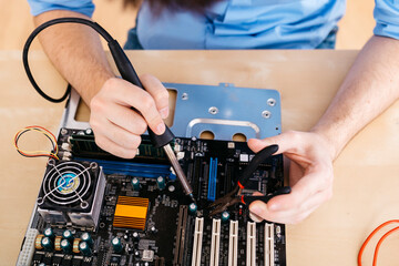 Close-up of technician repairing a desktop computer, soldering a component with tin